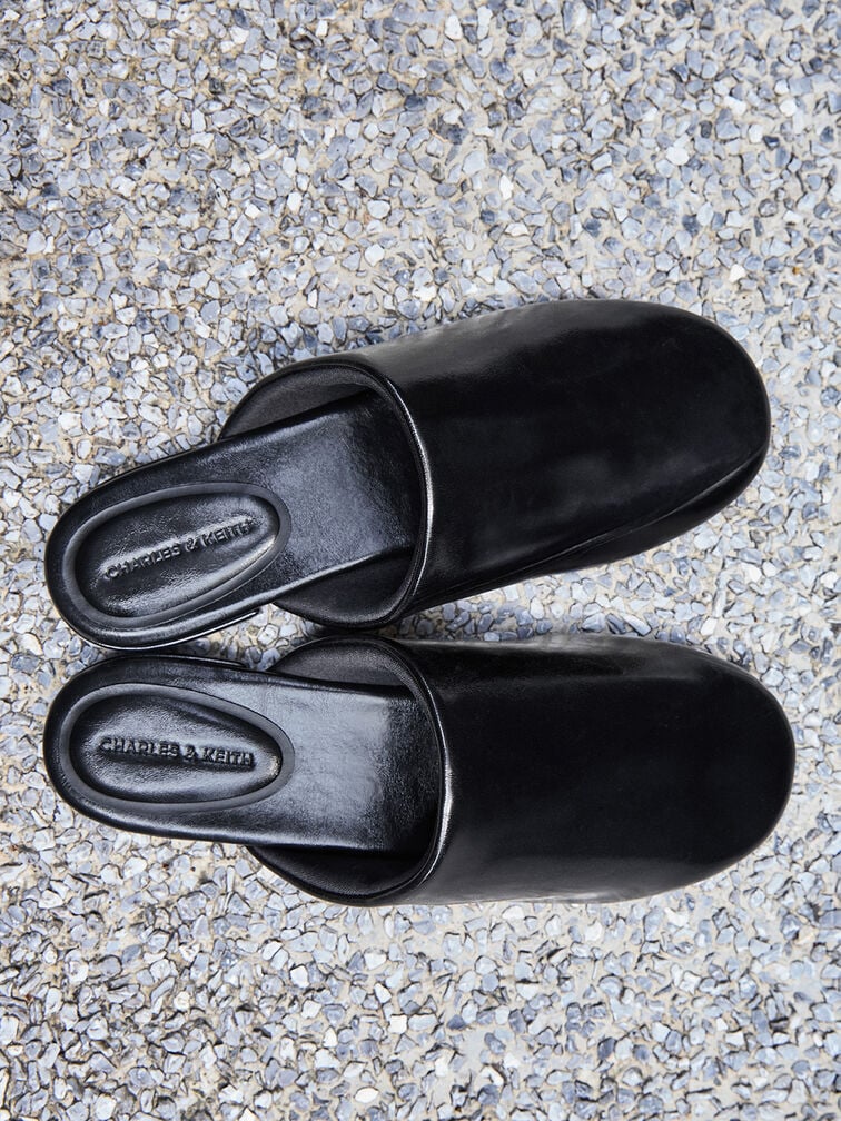Black flat mules with a backless, slip-on design.