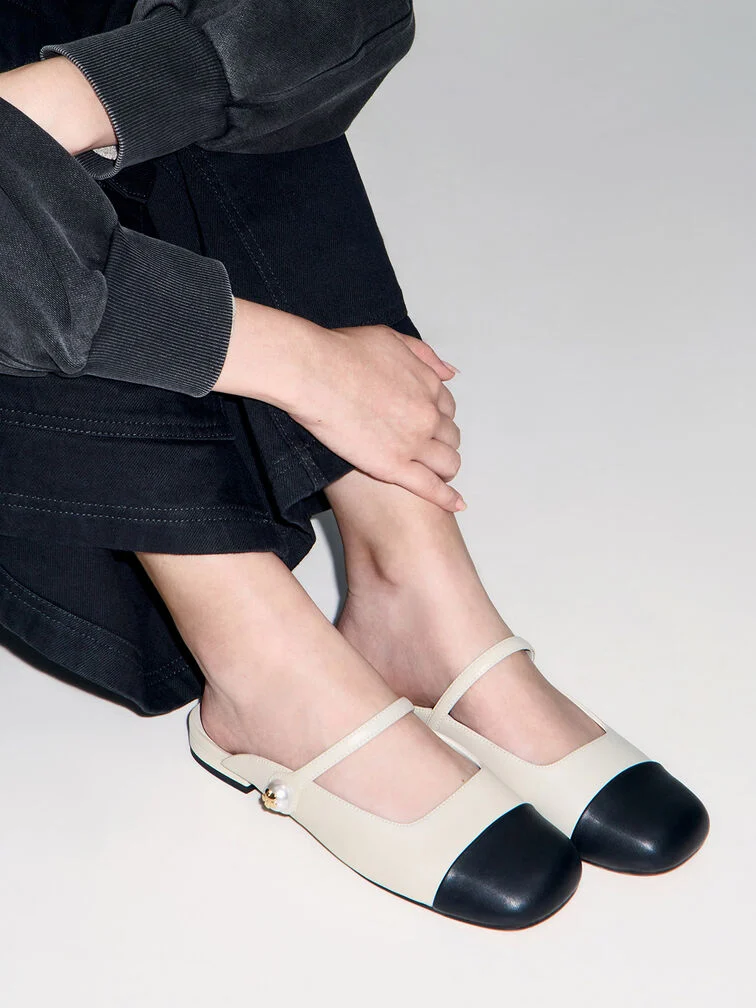 Cap-toe flat mules in black and white that are perfect for casual, everyday wear.