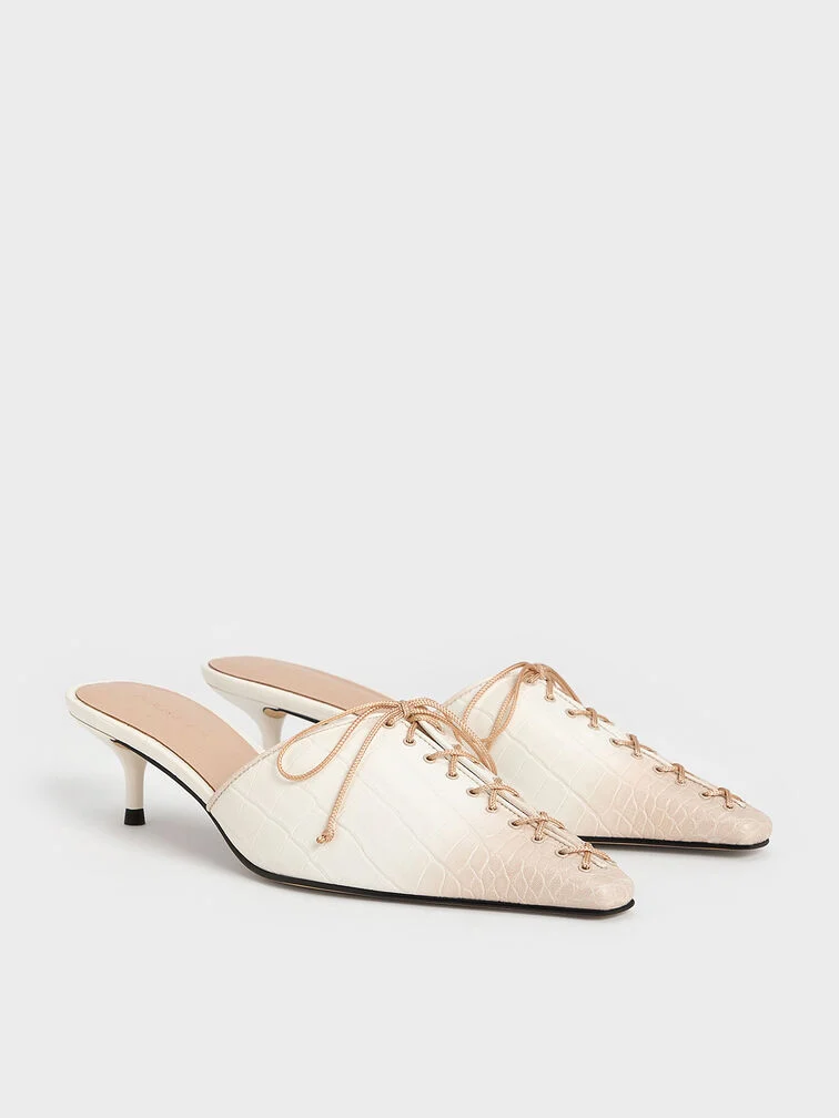 White mules featuring a kitten heel design.