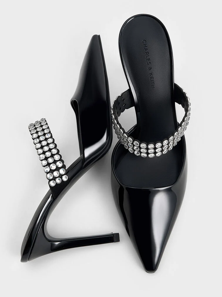 Patent black pointed-toe heeled mules adorned with crystal embellishments.