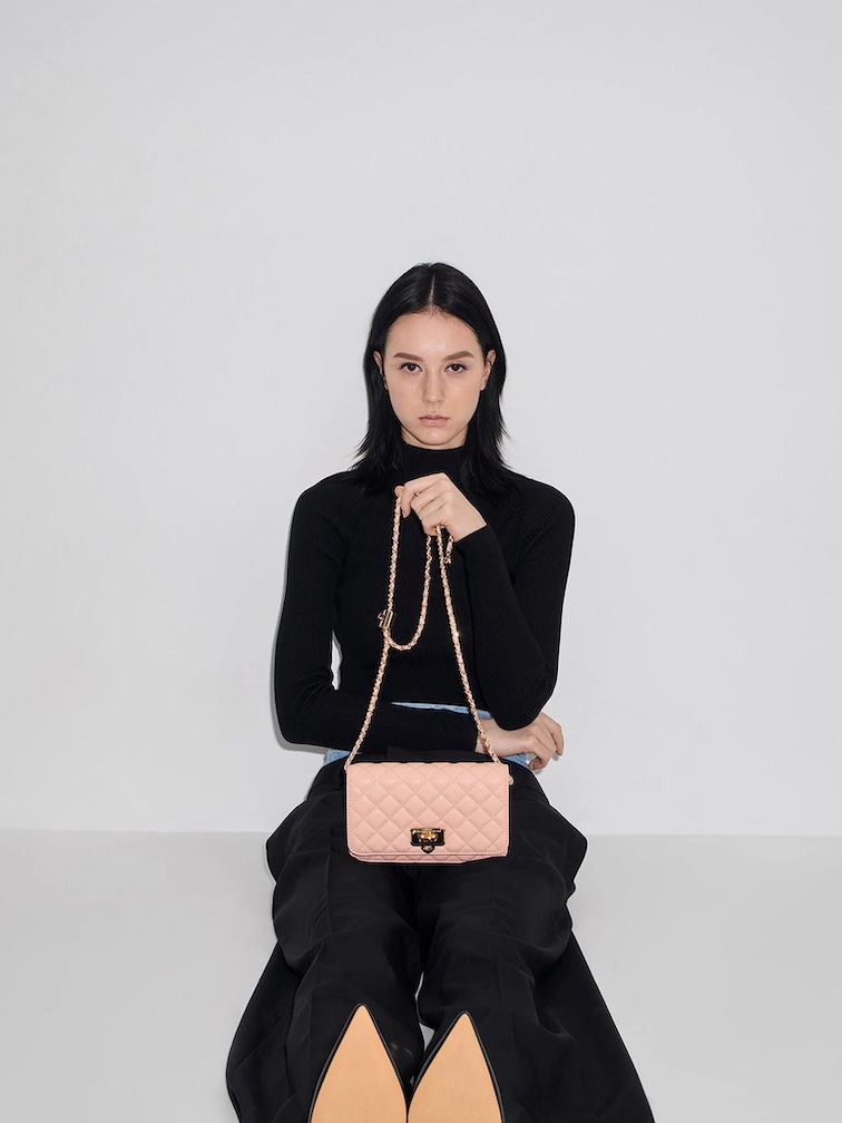 Structured quilted clutch with chain strap styled with black turtleneck and pants for a polished and professional work function look.