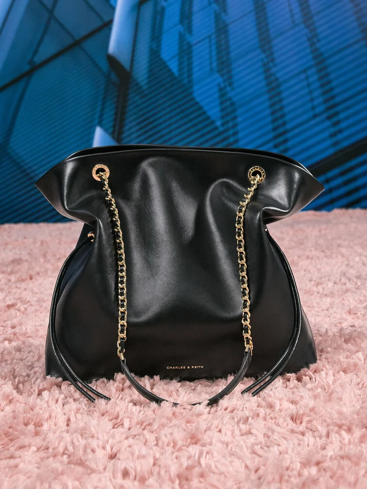 ドローストリングディテールと編み込みチェーンストラップ付きのトートバッグ。